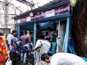 People filling water jars at a Dhaka WASA Water ATM booth in Mugdapara, Dhaka.
