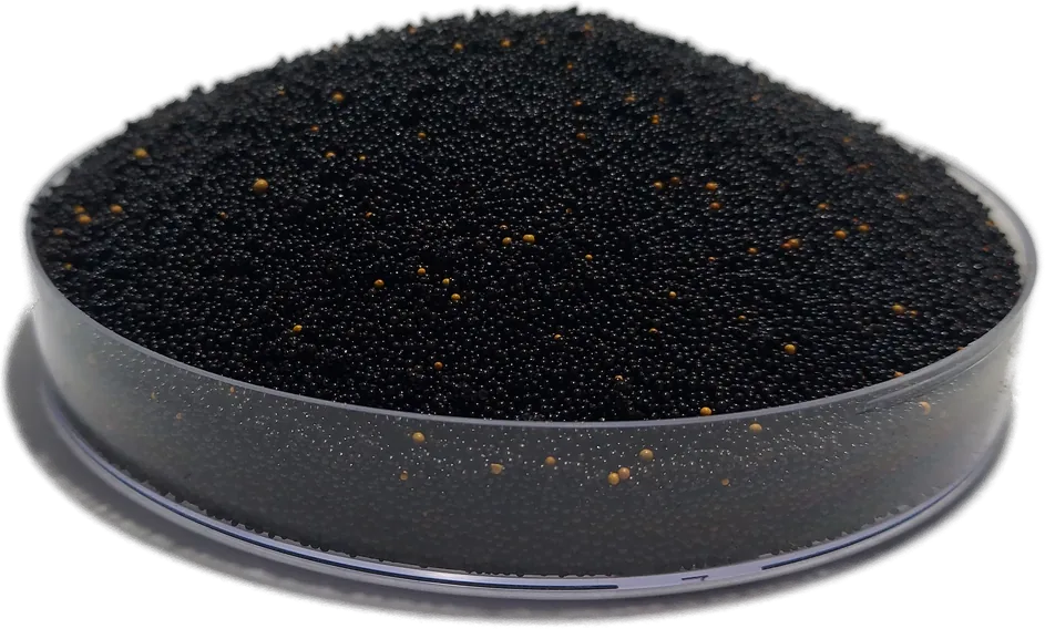 Black HIX-Nano 100+ arsenic removal beads flecked with amber, heaped in a laboratory dish.